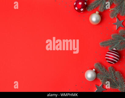 Christmas composition frame made of fir branches, baubles and stars ornaments on red background. Stock Photo
