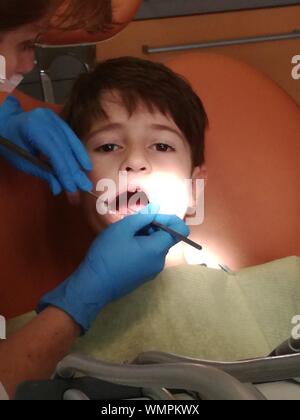 Cropped Hand Of Dentist Examining Boys Teeth In Clinic
