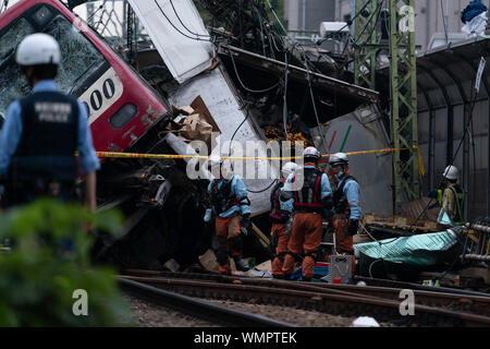 Fire brigade and policemen at the Kanagawa-Shinmachi station in Yokohama, Japan.A train collided with a truck that was stuck at the railroad crossing and at least 33 people were injured and one person died. Stock Photo