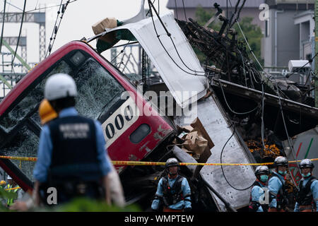 Fire brigade and policemen at the Kanagawa-Shinmachi station in Yokohama, Japan.A train collided with a truck that was stuck at the railroad crossing and at least 33 people were injured and one person died. Stock Photo