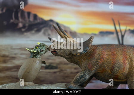 Triceratops with baby triceratops in foreground with cretaceous land in the background Stock Photo