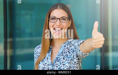 Young business woman shows thumbs up outdoors. Stock Photo