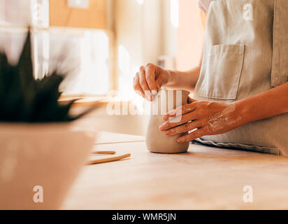 Hands of unrecognizable potter molding a mug at desk Stock Photo