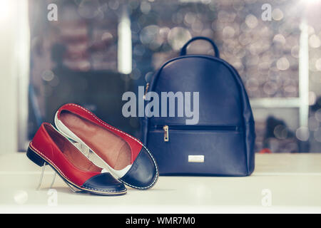 Pair of stylish women leather shoes with backpack in the background in a store. Stock Photo