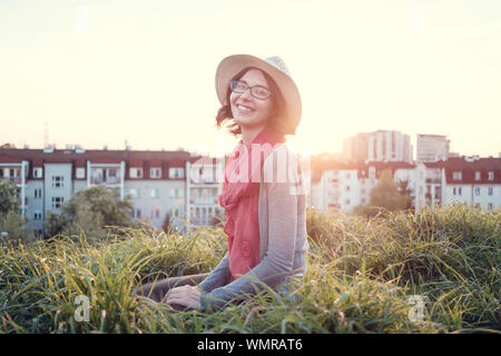 Beautiful young woman enjoying the sunset on top of a hill. Idea of rest and relaxation Stock Photo