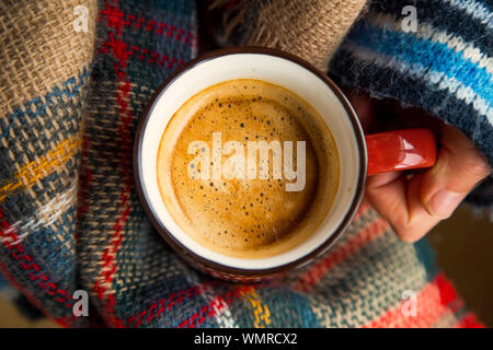 Cozy fall coffee cup top view, woman hands holding warm rustic autumn coffee cup with a cozy blanket, cozy fall still life Stock Photo