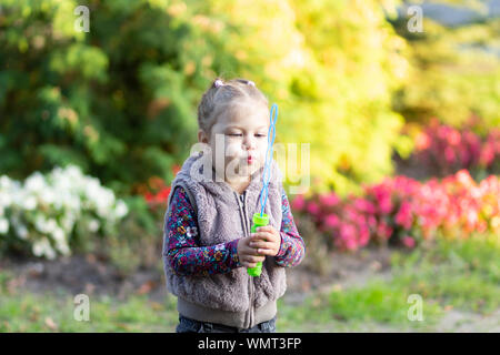 Portrait of little girl blowing soap bubbles in park Stock Photo