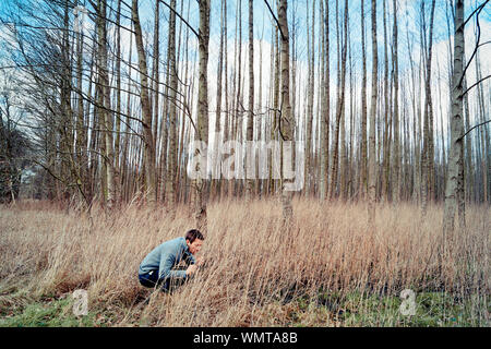 young man hiding in trees Stock Photo - Alamy