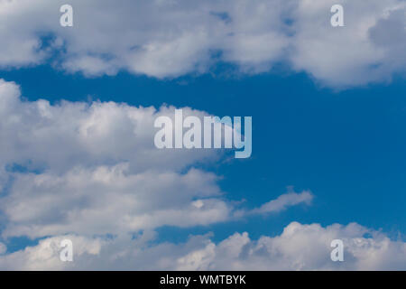 Slightly grey Cumulus clouds in a bright blue sky Stock Photo