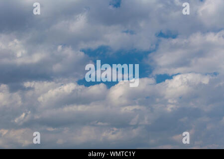Slightly grey Cumulus clouds in a bright blue sky Stock Photo