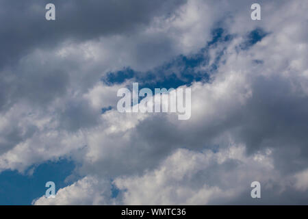 Slightly grey Cumulus clouds in a bright blue sky Stock Photo