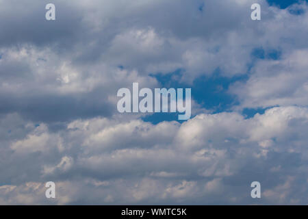 Slightly grey Cumulus clouds in a bright blue sky Stock Photo