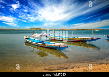Wooden canoe on sea lagoon in Senegal in Africa. It is the Saloum National Nature Park, a bird sanctuary. In the background is blue sky and the island Stock Photo