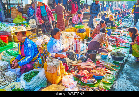 NYAUNGSHWE, MYANMAR - FEBRUARY 20, 2018: The line of fish vendors, selling the products from banana leaves in Mingalar Market, on February 20 in Nyaun Stock Photo