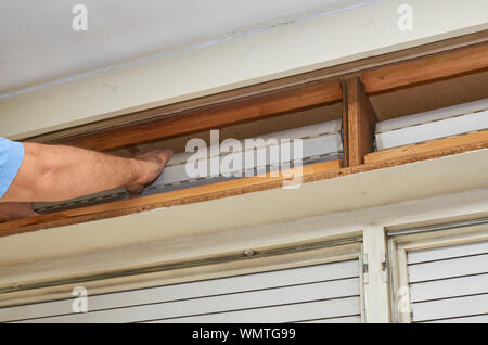Man fixing an old blind in its wooden box Stock Photo