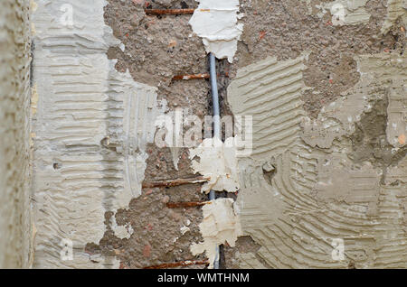 Installation of a new electric cable in a wall during renovation works in an apartment Stock Photo