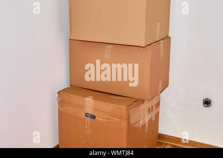 Three cardboard moving boxes in a corner of a room Stock Photo