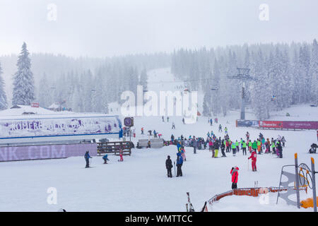 Kopaonik, Serbia - January 18, 2016: Panorama of ski resort Kopaonik during snowfall, people, skiers near ski lift, snowy trees at winter time Stock Photo