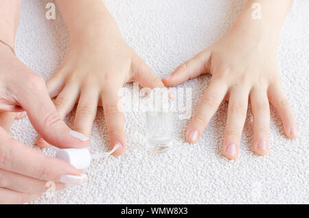 mother paints her child's nails with special nail polish by chewing finger nails Stock Photo