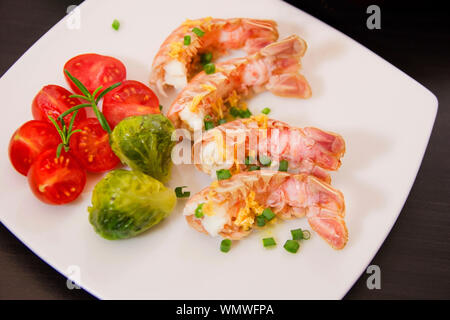 Langoustines or scampi on plate with cherry tomatoes and Brussels sprouts. Stock Photo