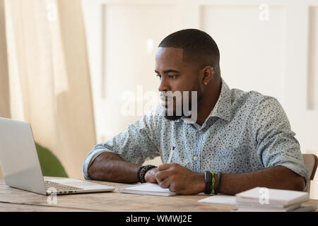 Concentrated millennial african american guy focused on online university courses. Stock Photo