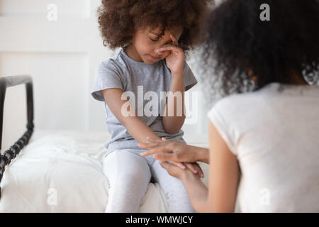 Mixed race mommy comforting upset little cute girl. Stock Photo