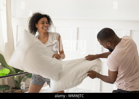 Young family couple having fun with pillow fighting. Stock Photo