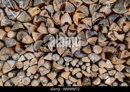 Stack of sawn tree logs detail. Stacked pile of wood logs stored for winter as firewood. Lumber industry. Wooden textured background Stock Photo