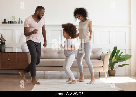 Happy african american family having fun, dancing at home. Stock Photo