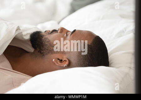 Close up african american guy lying on soft pillow. Stock Photo