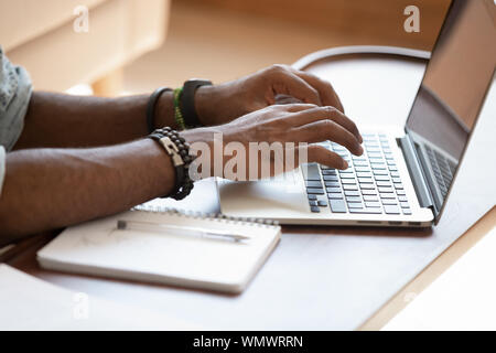 Close up cropped image young black man using laptop. Stock Photo