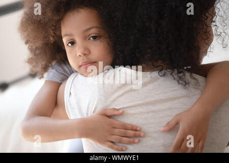 Upset little cute mixed race girl hugging mom. Stock Photo