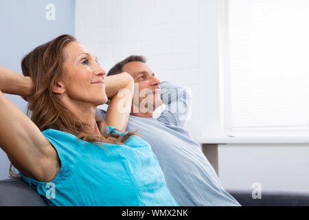 Mature Happy Couple Relaxing On Sofa At Home Stock Photo