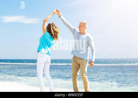 Portrait Of Happy Mature Couple Dancing On The Beach Stock Photo