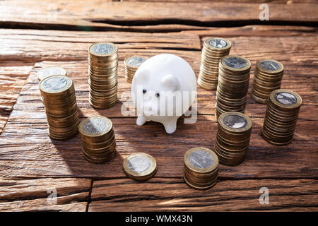 Close-up Of Pink Piggy Bank And Stacked Coins On Wooden Desk Stock Photo