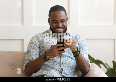 Addicted happy smiling african american guy using mobile phone. Stock Photo