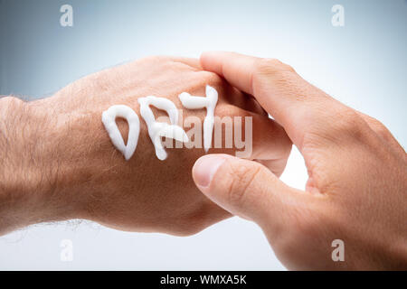 Close-up Of Dry Text Made With Lotion On Human Hand On White Background Stock Photo