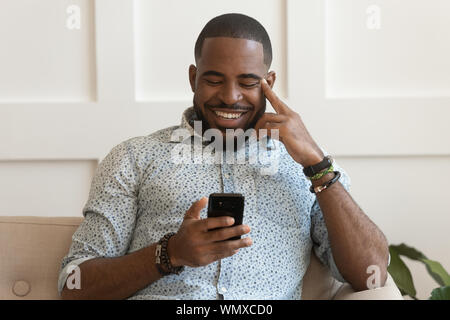 Happy smiling young african american guy holding cell phone. Stock Photo