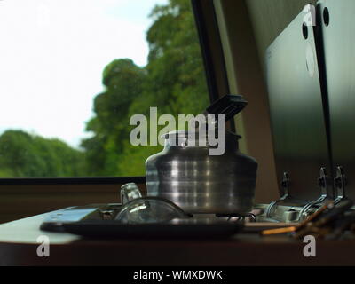 A photograph of a old style aluminium kettle on the smev cooker/stove of my campervan on a gloomy day in north wales Stock Photo