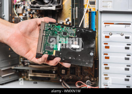 Closeup image of technician man hand changing the hard drive of pc computer . Maintenance and repair computer hardware service concept . Stock Photo