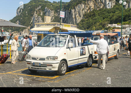 ISLE OF CAPRI, ITALY - AUGUST 2019: People with luggage at the taxi rank in the port on the Isle of Capri after arriving on a ferry. Stock Photo