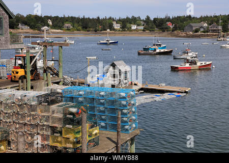 Lobster fishing boats in Bass Harbor with lobster traps on the dock of village of Bernard in foreground.Tremont.Maine.USA Stock Photo