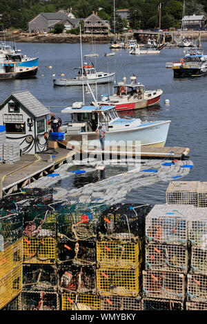 Lobster fishing boats in Bass Harbor with lobster traps on the dock of village of Bernard in foreground.Tremont.Maine.USA Stock Photo