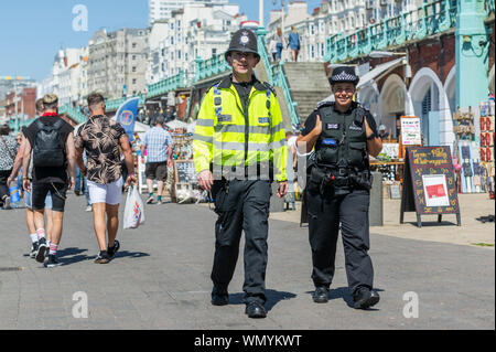 Police presence. Police patrolling the seaside promenade in Summer in Brighton, East Sussex, England, UK. Police patrol in Brighton Stock Photo