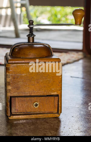 Rustic wooden vintage coffee grinder Single manual square shaped coffee grinder with little open drawer and metal handle Stock Photo