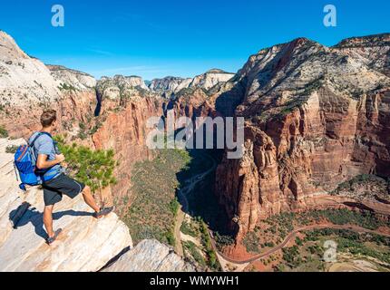 Young man, hiker standing at cliff, view from Angels Landing into Zion Canyon with Virgin River, Zion National Park, Utah, USA Stock Photo