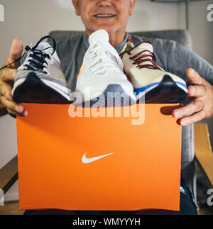 Paris, France - May 22, 2019: Happy senior man unboxing unpacking new Nike running shoes three diverse models Stock Photo