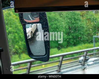 View of beige taxi car through the covered with raindrops windshield of bus coach or truck - motion on German autobahn Stock Photo