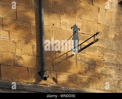 shadows of ironwork bracket typical local golden honey-coloured Cotswold stone building in High Street, Chipping Campden, Gloucestershire,England, UK Stock Photo