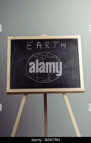 earth written on blackboard with earth symbol, background, high resolution, gray background Stock Photo